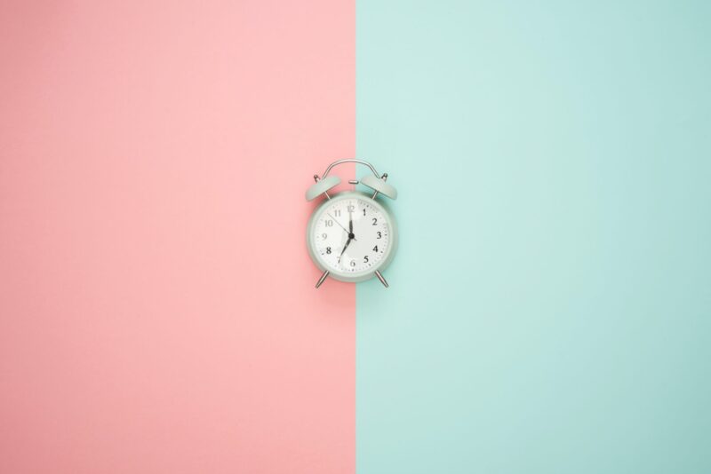 ピンク色と緑色の壁紙の前の目覚まし時計